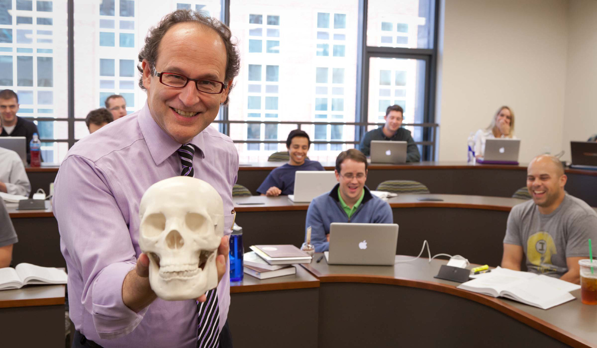 professor holding a skull in front of students